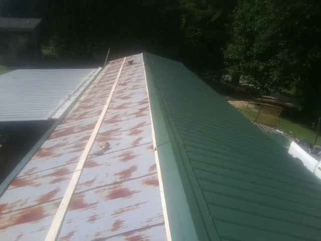 Old rusted panels beside newly installed green metal roofing — Wind Damage Roof Repair by Roofing Brothers in Greenfield